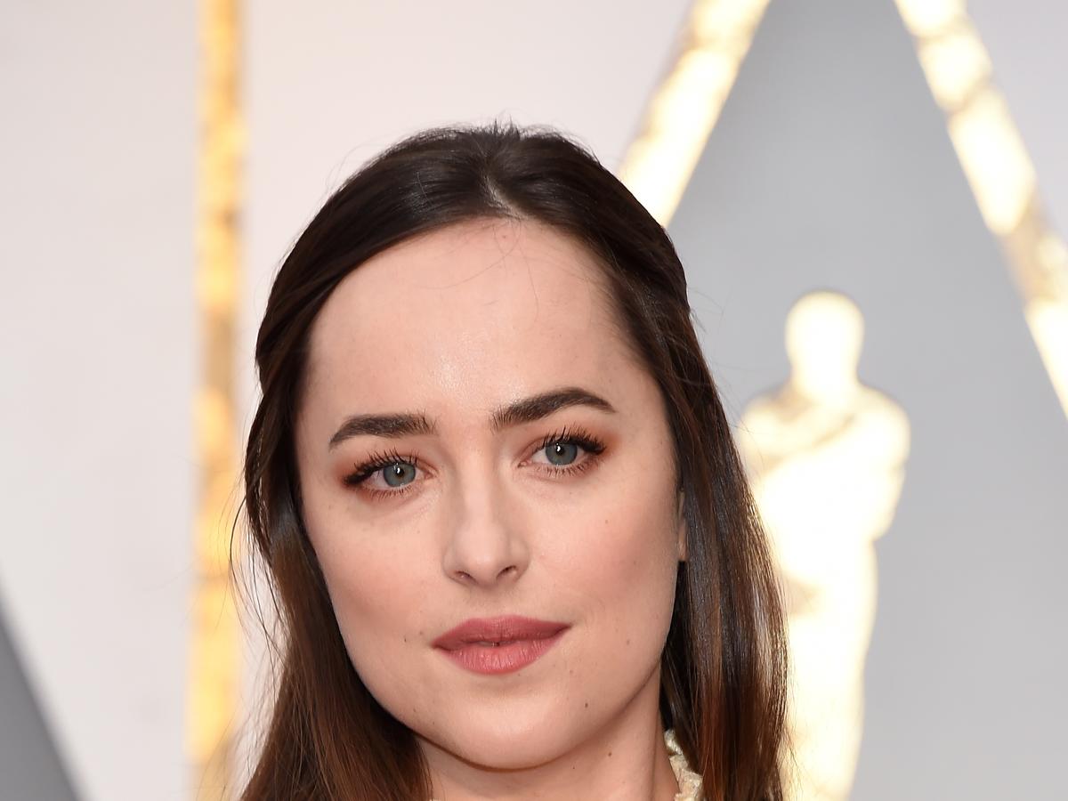 Dakota Johnson pozuje w złotej sukni na czerwonym dywanie podczas rozdania Oscarów 2017