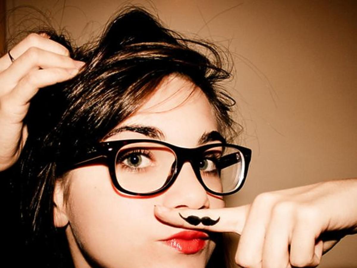 dziewczyna w okularach z namalowanym wąsikiem na palcu