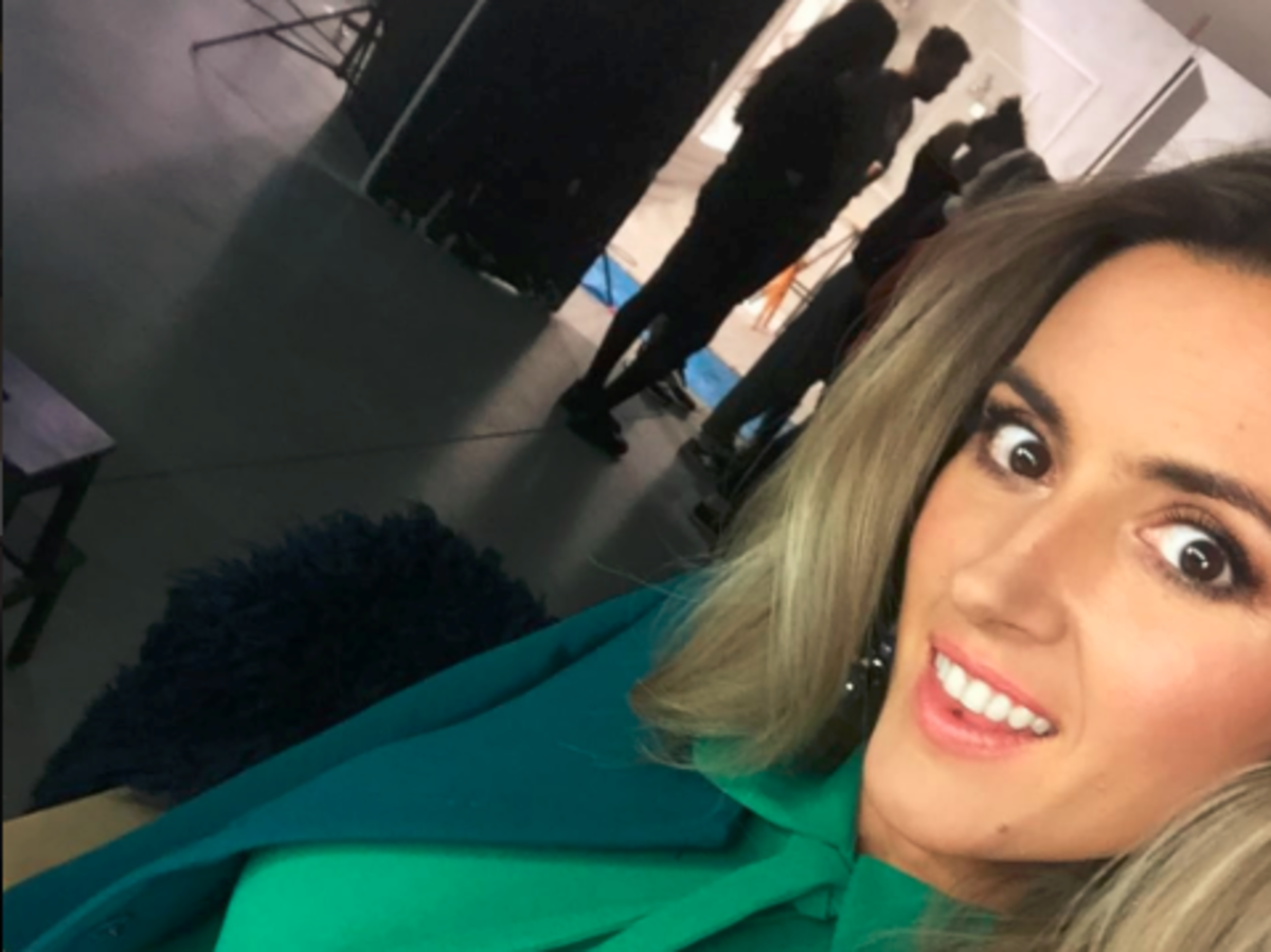 Karolina Szostak w blond włosach, zielonej bluzce i wzorzystej spódnicy