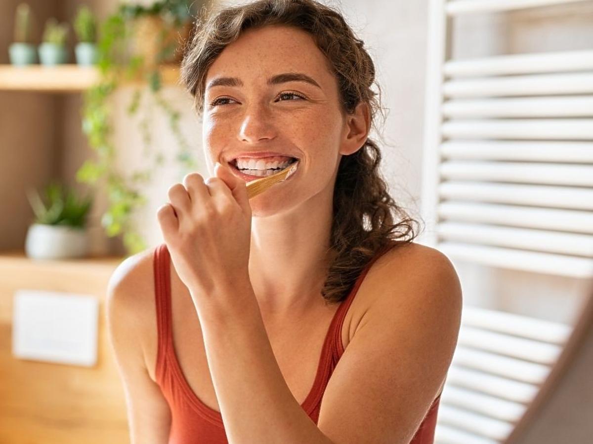 Kobieta myjąca zęby wybielającą pastą Pearl Drops Hollywood Smile
