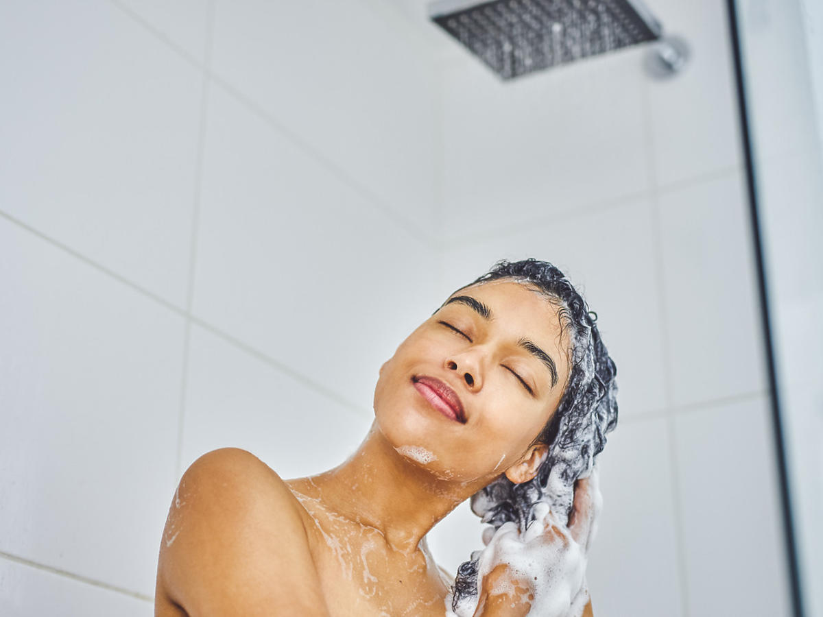 kobieta myje włosy szamponem na wypadanie włosów