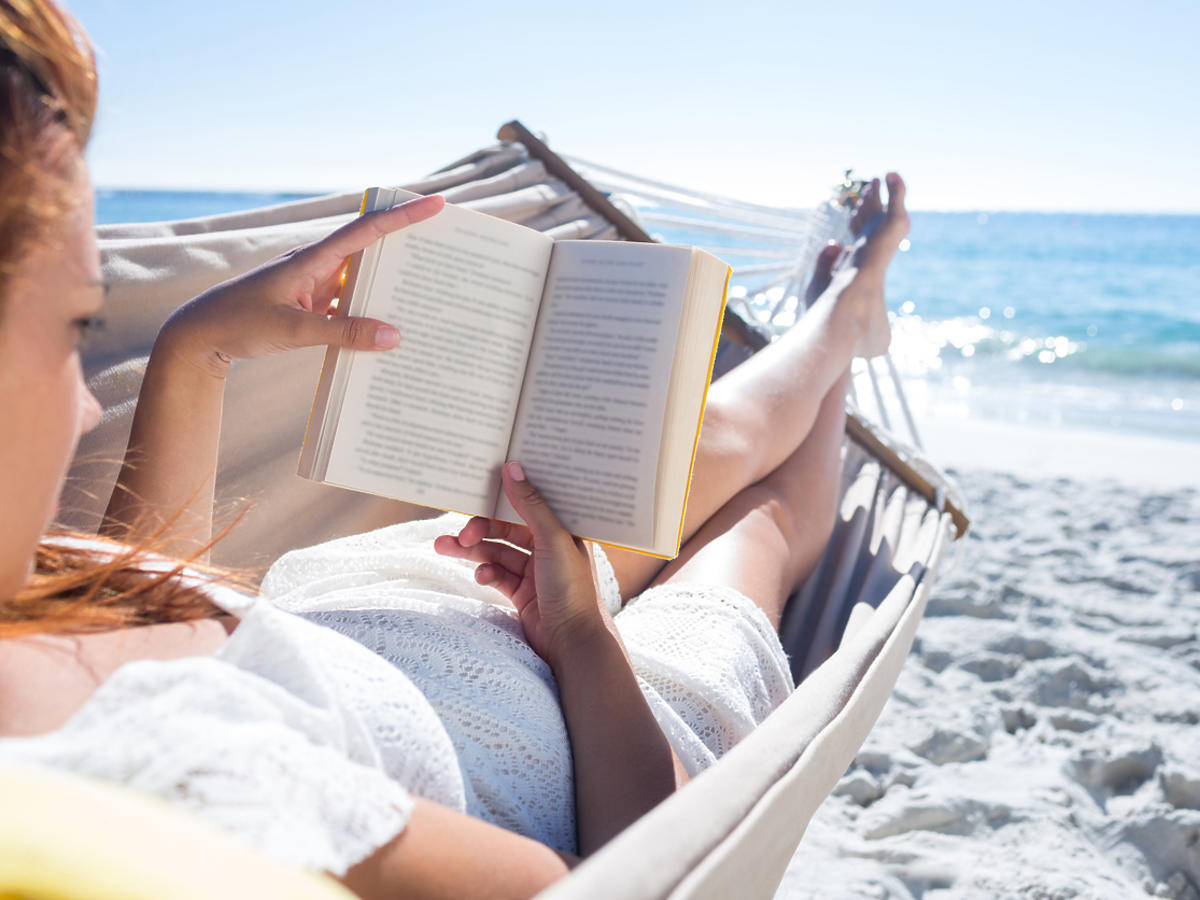 kobieta w hamaku z książką na plaży