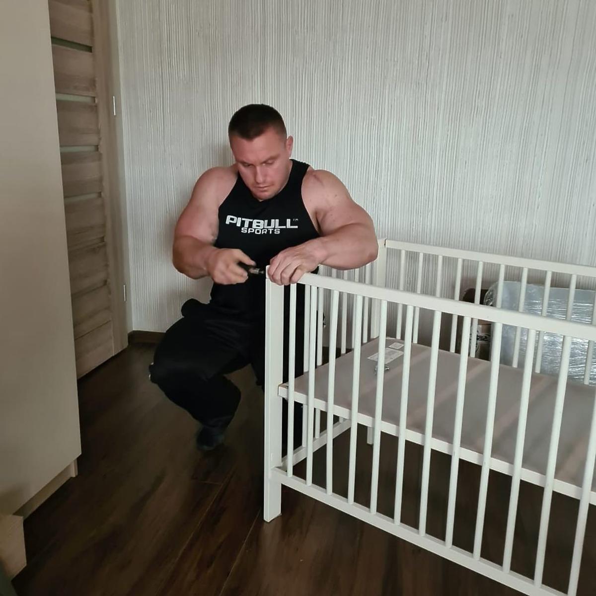 Krzysztof Radzikowski skręca łóżeczko dla dziecka