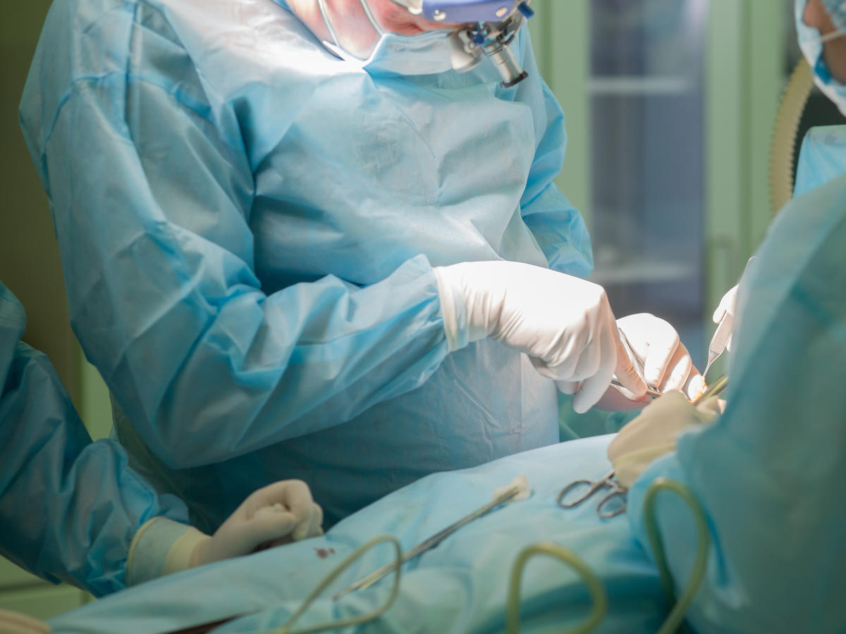 Lekarze w zielonych fartuchach operują na sali operacyjnej