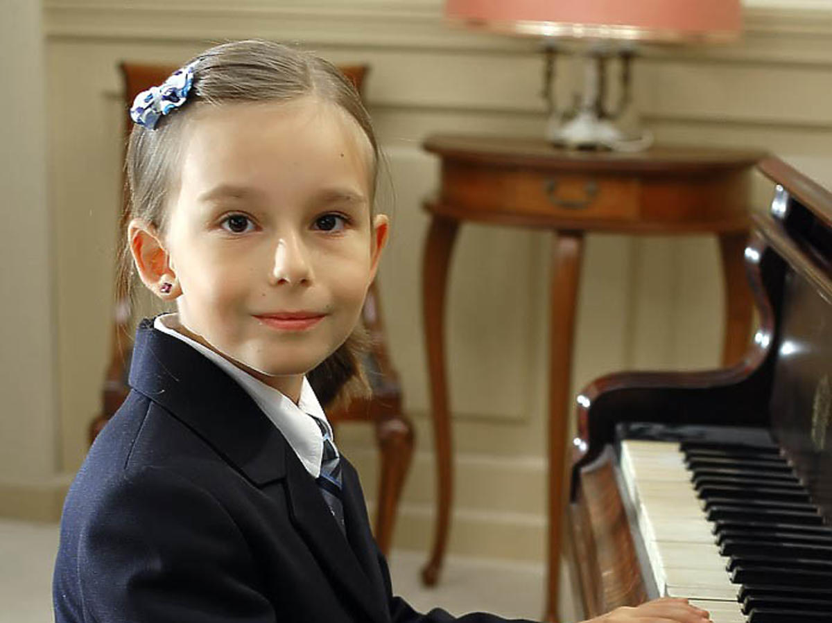Mała Emilka Kowalska siedzi przy fortepianie