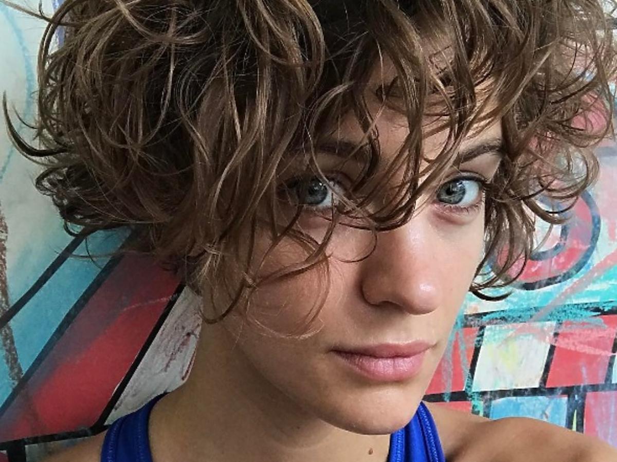 Renata Kaczoruk w kręconych włosach i niebieskiej koszulce pozuje do selfie