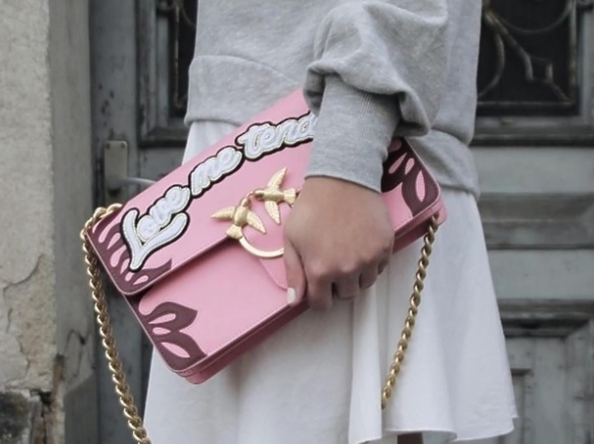 różowa torebka z napisem na łańcuszku dziewczyna trzyma torebkę